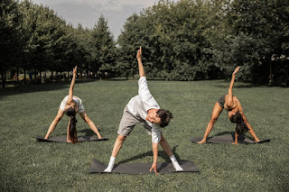 Three people enjoying their time away from their phones while spending time perfecting yoga poses A group of three outside of phoenix enjoy the nice weather with some yoga
