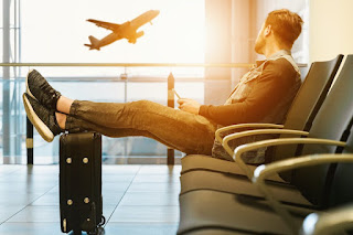 A man stretching his legs on his suitcase for a a little airport yoga preparation Pre-Flight Preparation: An image showing a traveler with a water bottle and wearing comfortable clothing, preparing for their flight.