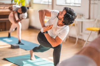 A man performing a twisting yoga pose in a group yoga class, focusing on alignment and breath control