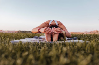 A person in a forward fold yoga pose on a mat outdoors, emphasizing flexibility and relaxation. Perfect for integrating yoga practice into nature for mental clarity.