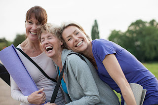 Holistic Yoga Community: Joy and Connection A group of women celebrating their yoga practice, laughing together and holding yoga mats after a holistic yoga class, demonstrating the joy and community aspect of yoga.
