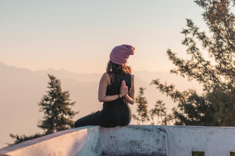 Person meditating in a peaceful outdoor setting during sunrise