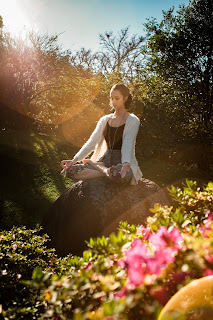 Individual using noise-canceling headphones for meditating in a busy public park