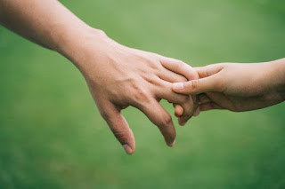 Two holding hands with a serine background