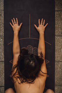 A woman practice with a guided metta meditation while holding the child’s pose on her yoga mat.