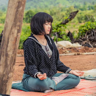 A woman peacefully meditating while surrounded by a beautiful red rock landscape