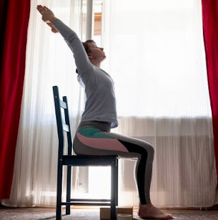Rehabilitation therapist assisting in adaptive chair yoga.