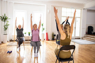 A group of seniors practicing chair yoga in a community setting, promoting physical well-being and social connection.