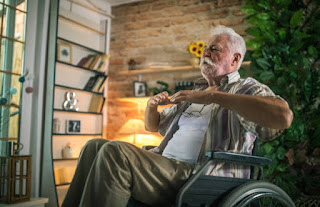 Elderly man practicing seated adaptive yoga in wheelchair