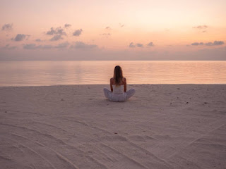 A solitary figure meditating on a beach at sunrise, capturing the stillness and clarity of jhana practice.