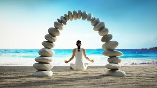 A woman meditating on a beach, framed by an arch of smooth stones, representing balance, mindfulness, and the stability of jhana practice.