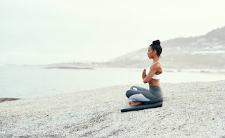 A person sitting in meditation by the ocean, embodying mindfulness and the Jhanas practice, connected to the boundless and formless nature of space and the self.