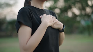 Close-up of hands placed on the chest during meditation in nature, representing a connection to the heart and the meditative practice of Jhanas, exploring the formless nature of self and infinite space.
