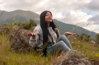 A woman practices mindfulness meditation in a natural setting, illustrating the power of nature and meditation to enhance focus and reduce stress.