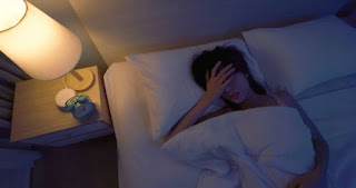 Person lying on a bed or yoga mat, eyes closed, with a gentle focus on relaxing muscles, peaceful facial expression, cozy indoor space, evening light.
