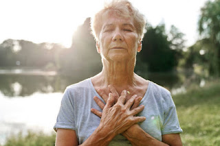 Close-up of hands resting on chest and abdomen, deep breathing, calm and relaxed posture, focus on breath, nighttime setting.