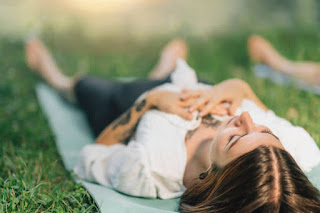 Person practicing meditation with hands over heart, gentle smile, outdoor or indoor setting with soft, warm lighting, emphasizing compassion and tranquility.