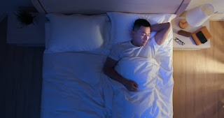 Person visualizing a peaceful scene like a beach or forest, serene expression, lying on a bed, calming bedtime environment, dim lighting