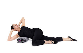 Person practicing a gentle supported twist on a yoga bolster, lying in a cozy living room or yoga studio, focus on relaxation and support