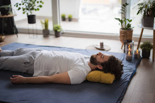 Person practicing gentle yoga with candles or soft lamp light, focusing on relaxation before bedtime, serene and calming atmosphere