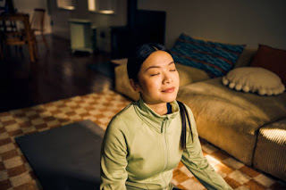 A woman meditating indoors with a gentle expression of peace, working towards achieving access concentration for deeper absorption in Jhana practice."