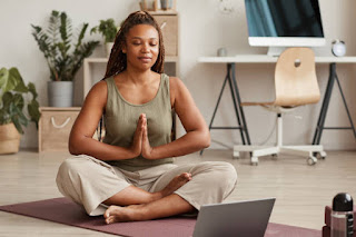 A woman meditating on a yoga mat in her living room, demonstrating the practical integration of Jhana meditation insights into everyday life for balance and equanimity.