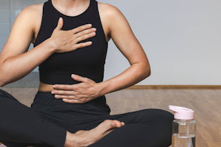 Hands on abdomen practicing deep breathing to support mental clarity and reduce brain fog.