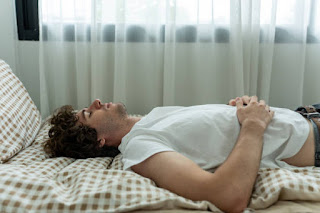 Man practicing 4-7-8 breathing in bed to induce relaxation and improve sleep quality.