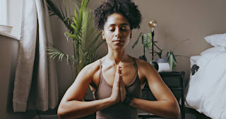 A person in Child’s Pose on a yoga mat, in a dimly lit, serene room.