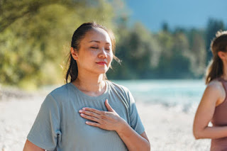 A person sitting cross-legged in a quiet room with eyes closed, practicing deep breathing.