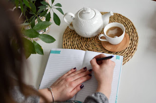 Open journal with a pen and a mug of tea, representing a calm space for reflecting on challenges.