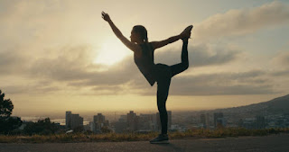 Person practicing yoga outdoors at sunrise, representing an energizing morning yoga sequence to boost motivation.