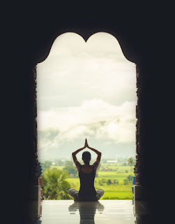 Person practicing yoga in natural light, embodying the peaceful spirit of Bhakti Yoga.