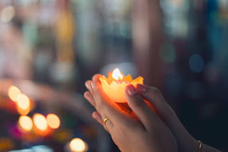 Close-up of hands holding a candle, symbolizing universal devotion in Bhakti Yoga.