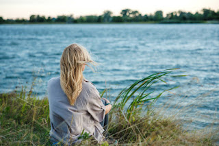 Person meditating in a calm setting with natural elements, representing rest through mindfulness and meditation.