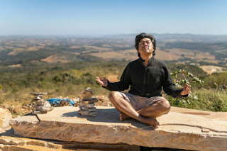 Person meditating in an open space with vast sky, representing the expansive awareness of the ether element.