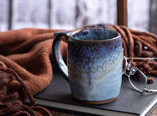 A warm cup of tea by the window in Seattle, with soft winter rain falling outside, symbolizing the comfort and contentment of Santosha.