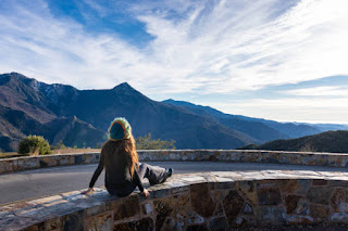 A person meditating on a mountaintop at sunrise, with a tranquil, expansive view symbolizing inner stillness and peace.
