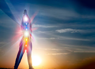 A silhouette of a person standing with chakras glowing along the spine, symbolizing kundalini energy awakening and alignment at sunrise.