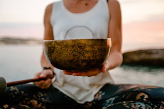 Close-up of a person holding a Tibetan singing bowl outdoors, symbolizing the power of sound healing and vibrational energy in Kundalini Yoga.