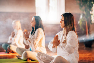 A group of people meditating in a yoga studio with soft light and incense smoke, illustrating the collective energy and spiritual community in Kundalini Yoga.