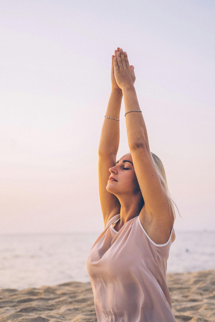 Woman practicing yoga sun salutations outdoors at sunrise, illustrating morning yoga energy and clarity.