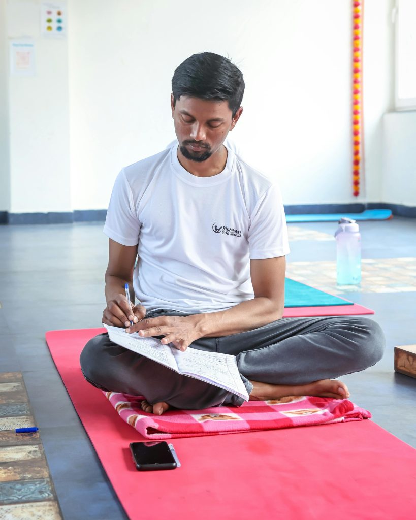 A man is tracking his pain management and daily symptoms in his journal or notebook to help him keep track and see what is working and what isn't.