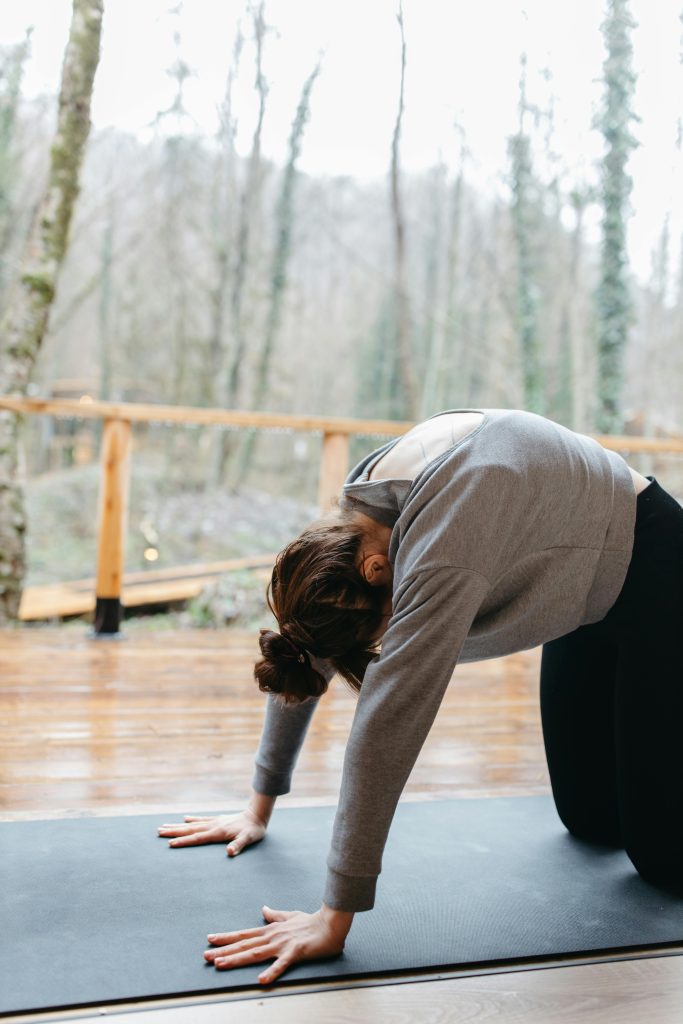 Woman performing Cat-Cow yoga flow to release deep fascia