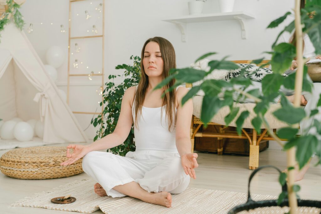 Person meditating with glowing energy rising along spine, representing Kundalini awakening.