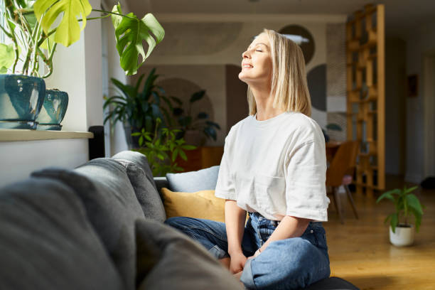 A woman sitting in her home embracing the sunlight after a deep monthly reflection on her goals